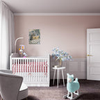 A styled nursery room featuring a white wooden crib with pink bedding, a small white side table with blue flowers, a light blue plush rocking horse, and a dusty pink wall with white paneling.