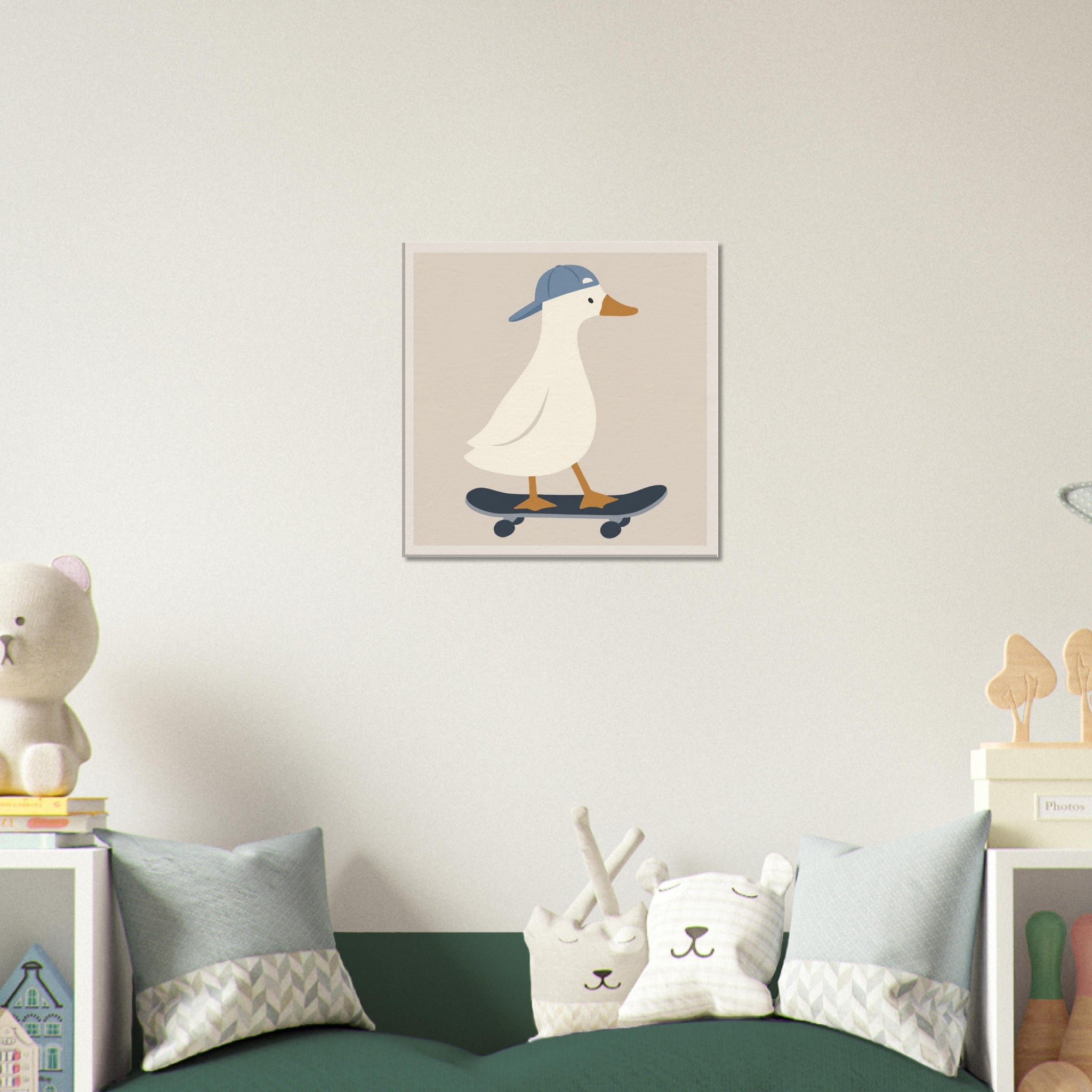 A square wall art print featuring a white duck wearing a blue cap and riding a dark skateboard, displayed above a green sofa in a styled nursery setting with pillows and toys.