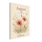 A vertical canvas print featuring a vintage-style floral illustration with the name 'August' at the top and 'Olivia' at the bottom, shown at a slight angle on a white background.